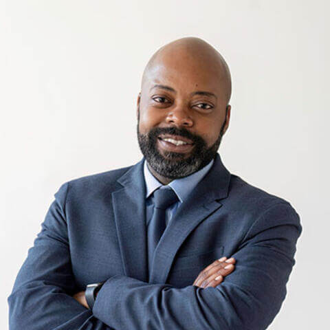 Marchon Jackson, smiling while wearing a blue suit, blue tie and light blue shirt.