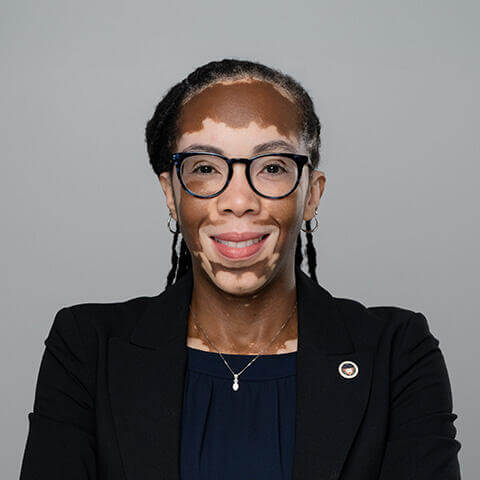 Kim Lewis smiling and wearing a Howard University pin on her blazer