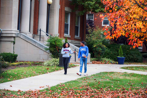 A pair of students in Howard-brand sweaters happily conversing on Howard University campus.