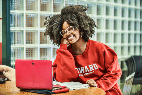 A student in a Howard sweatshirt with a laptop.