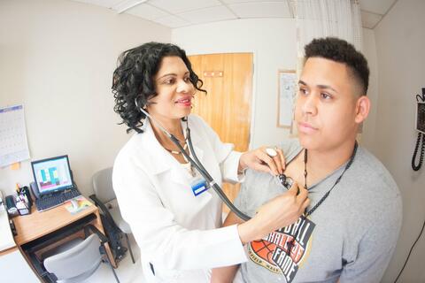 A doctor using a stethoscope to listen to a patient's heart.