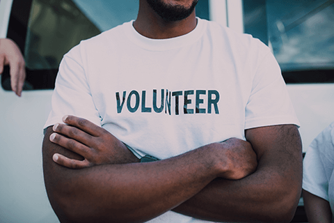 A closeup of a man wearing a volunteer shirt.