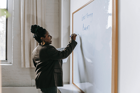 A teacher writing on a white board.