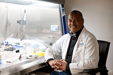 Man seated and smiling next to medical equipment