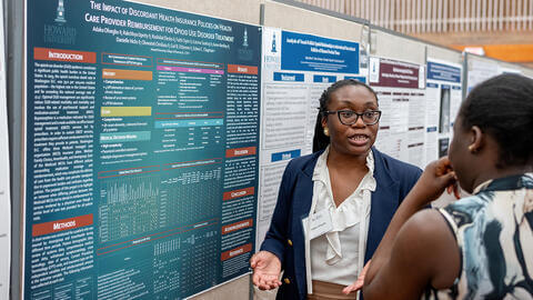 Professional explaining a presentation with data to a student at a conference