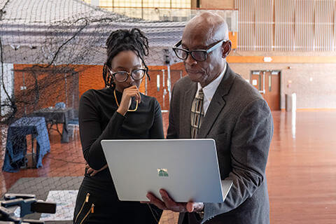 Student and mentor looking at a laptop screen