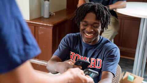 Howard students smiling and using their cellphones to network